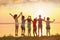 Little children jumping near river at sunset, back view