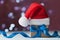 Little christmas gift box or present and santa hat against magic bokeh background. Holiday greeting card.