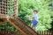 Little climber takes the rope bridge. Boy has fun time, kid climbing on sunny warm summer day