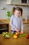 Little cook cooks salad. On a table various vegetables.