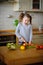 Little cook cooks salad. On a table various vegetables.