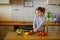 Little cook cooks salad. On a table various vegetables.