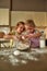 Little cooks. Adorable little children, boy and girl in aprons looking focused while preparing dough together on the