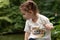 Little cool redhead girl with ponytails against the backdrop of a pond and a blurred green background