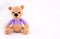 Little crocheted teddy bear on a gray background. A soft bear cub in lilac clothes. Copy space