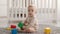 Little curious baby playing with colorful cubes, sitting on floor at bedroom , looking upward with interest, panorama