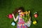 Little curly girl with bouquet of tulips lying in green lawn.