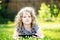 Little curly girl lying on the grass and holds in hands tablet.