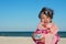 Little curly girl screaming and being capricious at the sea beach