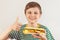 Little cut boy recommends and likes tasty cheeseburger on white background