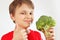 Little cut boy in a red shirt recommends fresh broccoli on white background