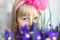 Little cute adorable blond caucasian female child girl portrait with beautiful blue eyes holding fresh purple iris flower bouquet