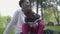 Little cute African American boy playing with plastic toy in the park, sitting on mother`s laps close up. The woman and