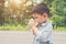 Little cute asian boy drinking water from the glasses on the roadside,tired for play.