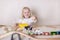 Little cute baby boy 3 years old drinks milk with cookies and plays in the wooden station train set on the table