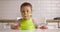 Little cute baby boy sits at the table and plays with a spoon. Concept of happy child at the kitchen.