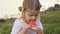 Little cute baby girl eat red watermelon sits on the green grass by the pond