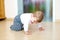 Little cute baby girl learning to crawl. Healthy child crawling in kids room. Smiling happy healthy toddler girl. Cute