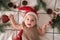 Little cute baby girl portreit in red christmas santa hat with lights top view. Christmas holidays