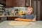 Little cute blond boy in kitchen prepares pie dough by rolling it out on table with rolling pin