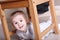 Little cute blond girl in striped shirt on floor under stool