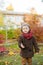 Little cute boy in an autumn coat and cap plays in an autumn park with yellow leaves