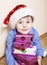 Little cute boy with Christmas gifts at home. close up emotional face on boxes in santas red hat