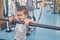 Little cute boy grimacing, holding on metallic crossbar in gym.