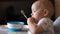 Little cute boy happily eating baby porridge with his hands and genuinely smiles