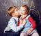 Little cute boy kissing blonde girl in classroom at blackboard, first school love, lifestyle people concept