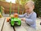 A little cute boy of one and a half years plays with toy car at the playground. Adorable toddler playing with cars and toys