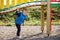 A little cute boy plays under a beautiful, curved bridge on a colorful playground. An agile child actively spends time in the