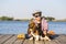 Little cute boy is sitting by the river with his dog