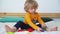 little cute boy of two years old plays children's constructor sitting on the bed