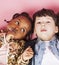 Little cute caucasian boy and african american girl hugging playing on pink background, happy smiling diverse nation and