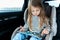 Little cute caucasian girl is driving in car. Online school learning,education.Playing video games in tablet. Traveling on road in