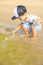 Little cute caucasian toddler boy with blond hair plays at the beach in sea waves on sunny summer day. Family vacation with kids