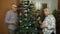 Little cute child girl with senior grandparents family decorating artificial Christmas tree at home