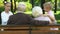 Little cute children happily talking with grandparents sitting on bench in park