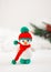 Little cute crocheted snowman in a red hat and scarf on a white background