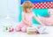 Little cute curly girl in pink pajamas watching the book sitting on the floor in children\'s bedroom.