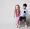 Little cute frolic kids Asian boy and blonde girl play hide and seek together, stand holding hands looking at copy space