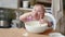 Little cute funny girl licking the dough from her finger helping mother prepare pie cake in kitchen, baking homemade