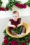 Little cute girl 1 year old in a dress of Marsala color with a wicker basket with peonies. Spring and flowers.