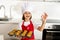 Little and cute girl alone in cook hat and apron presenting and showing tray with muffins smiling happy