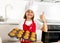 Little and cute girl alone in cook hat and apron presenting and showing tray with muffins smiling happy