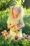 Little cute girl with blond hair collects the apples scattered