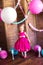 Little cute girl with blond hair in a pink dress and a princess crown with large bright balloons and garlands. Children`s holiday.