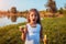 Little cute girl blowing soap bubbles in summer park by river. Closeup. Kid having fun