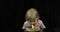 Little cute girl blows out festive candle on birthday cake on black background